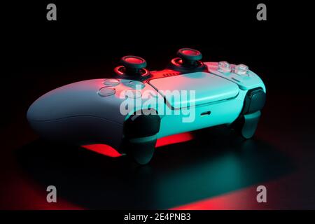 Modernes weißes Gamepad in rot und blau beleuchtet. Game Controller für Videospiele und E-Sports auf dunklem Hintergrund. Stockfoto