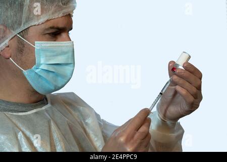 Eine Krankenschwester bereitet eine Dosis Impfstoff zu injizieren gekleidet in persönliche Schutzausrüstung (PSA). COVID-19 Konzept Stockfoto