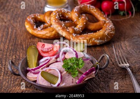 bayerischer Wurstsalat auf dunklem Holz Stockfoto