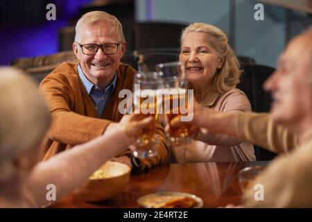 Porträt von lächelnden älteren Menschen trinken Bier in der Bar und Klirrende Gläser, während Sie die Nacht mit Freunden genießen Stockfoto