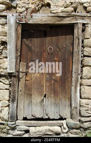 Ein rostiger Hufeisen wurde an einer verwitterten Tür aus genagelt Holzbohlen Stockfoto