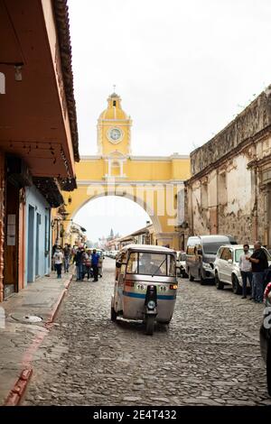 Tuk-Tuk öffentlichen Verkehrsmitteln Fahrzeug durch die Santa Catalina Arch in Antigua, Guatemala, Mittelamerika Stockfoto