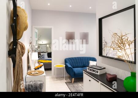 Stilvolles Interieur eines neu renovierten modernen Studio-Apartments. Blick von der Eingangstür mit Kleiderbügel und Spiegel zum Wohnbereich Stockfoto