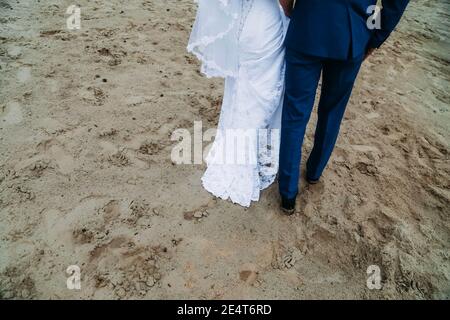 Braut und Bräutigam laufen auf dem Sand. Spaziergang entlang der Küste Stockfoto