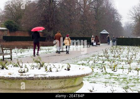Mann mit einem roten Regenschirm ging im Schnee und Im London greenwich Park können Sie Spaß haben Stockfoto