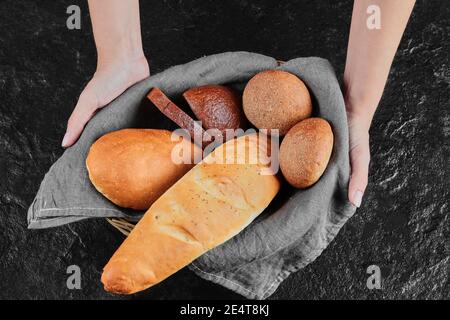 Frau Hand hält frisch hausgemachtes Brot auf dunklem Hintergrund Stockfoto