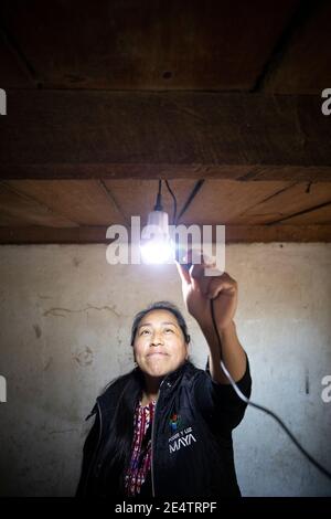 Ein Techniker von einem lokalen gemeinnützigen Energieversorger testet ein neues solarbetriebenes Beleuchtungssystem in einem Haus in Cantel, Guatemala, Centr Stockfoto