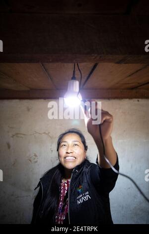 Ein Techniker von einem lokalen gemeinnützigen Energieversorger testet ein neues solarbetriebenes Beleuchtungssystem in einem Haus in Cantel, Guatemala, Centr Stockfoto