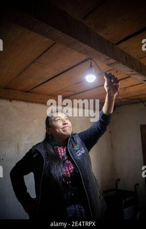 Ein Techniker von einem lokalen gemeinnützigen Energieversorger testet ein neues solarbetriebenes Beleuchtungssystem in einem Haus in Cantel, Guatemala, Centr Stockfoto