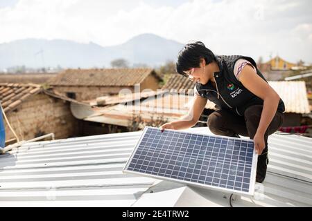 Ein Techniker von einem lokalen gemeinnützigen Energieversorger installiert ein neues solarbetriebenes Beleuchtungssystem auf einem Haus in Cantel, Guatemala. Stockfoto