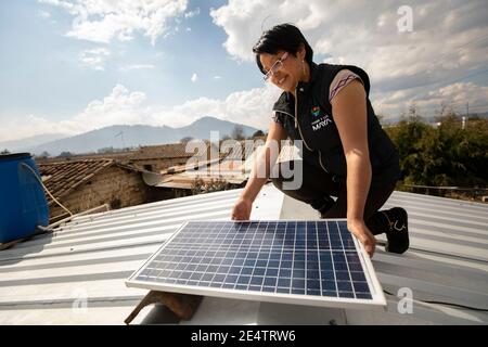 Ein Techniker von einem lokalen gemeinnützigen Energieversorger installiert ein neues solarbetriebenes Beleuchtungssystem auf einem Haus in Cantel, Guatemala. Stockfoto