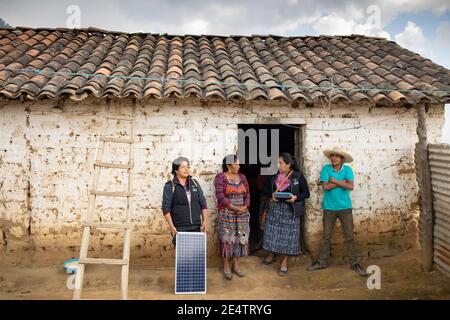 Ein Techniker von einem lokalen gemeinnützigen Energieversorger installiert ein neues solarbetriebenes Beleuchtungssystem auf einem Haus in Cantel, Guatemala. Stockfoto