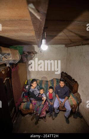 Familie, die ein neues solarbetriebenes Beleuchtungssystem in ihrem Zuhause in Cantel, Guatemala, Mittelamerika, verwendet. Stockfoto