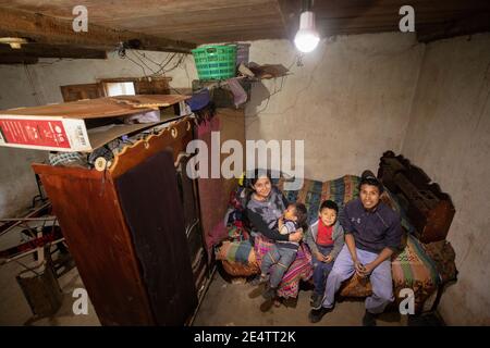 Familie, die ein neues solarbetriebenes Beleuchtungssystem in ihrem Zuhause in Cantel, Guatemala, Mittelamerika, verwendet. Stockfoto