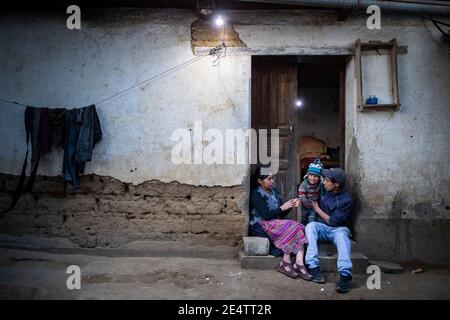 Familie, die ein neues solarbetriebenes Beleuchtungssystem in ihrem Zuhause in Cantel, Guatemala, Mittelamerika, verwendet. Stockfoto