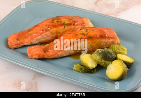 Lachsfischfilets mit Weißweinsauce und rosenkohl Auf blauer Servierplatte Stockfoto