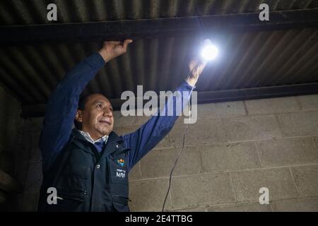 Ein Techniker von einem lokalen gemeinnützigen Energieversorger testet ein neues solarbetriebenes Beleuchtungssystem in einem Haus in Cantel, Guatemala, Mittelamerika. Stockfoto