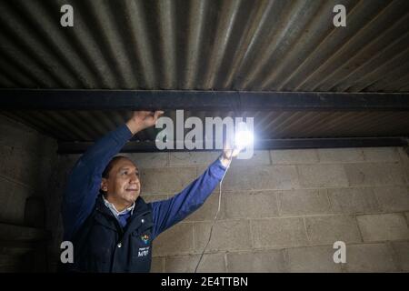 Ein Techniker von einem lokalen gemeinnützigen Energieversorger testet ein neues solarbetriebenes Beleuchtungssystem in einem Haus in Cantel, Guatemala, Mittelamerika. Stockfoto