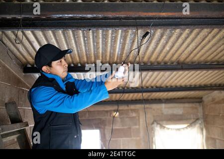 Ein Techniker von einem lokalen gemeinnützigen Energieversorger testet ein neues solarbetriebenes Beleuchtungssystem in einem Haus in Cantel, Guatemala, Mittelamerika. Stockfoto