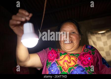 Eine Frau schaltet ihr solarbetriebenes Licht zum ersten Mal in ihrem Haus in Cantel, Guatemala, Mittelamerika, an. Stockfoto