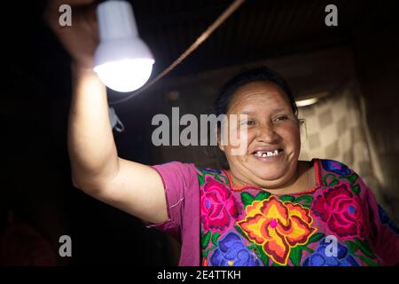 Eine Frau schaltet ihr solarbetriebenes Licht zum ersten Mal in ihrem Haus in Cantel, Guatemala, Mittelamerika, an. Stockfoto