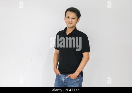 Porträt eines lächelnden jungen asiatischen Mannes mit schwarzem Hemd und Jeans-Hose isoliert auf weiß. Stockfoto