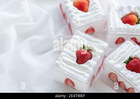 Erdbeer-Shortcake in Kunststoffbox auf mit Stoffhintergrund und Kopierraum, Minimal-Kuchen und Bäckereikonzept Stockfoto