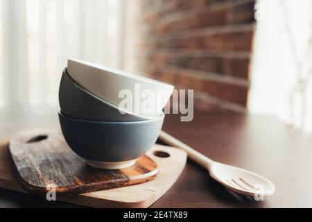 Drei Keramikschalen, Holzlöffel auf einem braunen Holztisch. Unscharfer Hintergrund Stockfoto