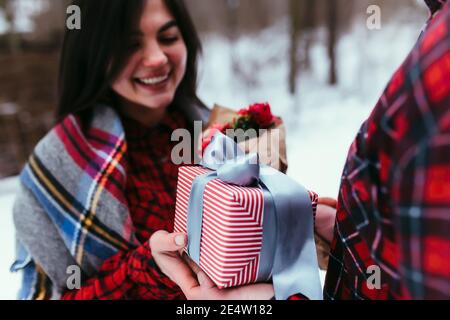 Hände geben eine Geschenkbox mit Band. Unscharfer Hintergrund Stockfoto