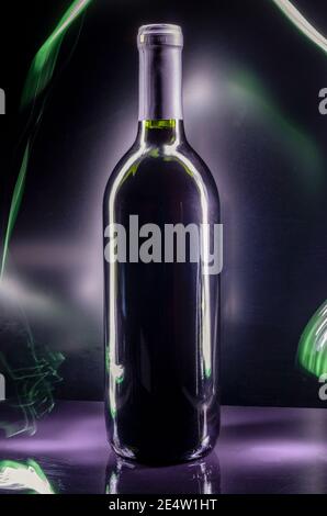 Schwarze Flasche Wein auf schwarzem Hintergrund mit Licht Schienen und Reflexionen Stockfoto