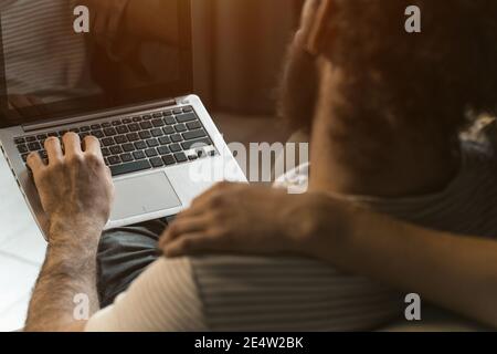 Schuss von hinten. Arbeiten zusammen junges Paar zu Hause unter Quarantäne mit sitzen auf den Sesseln. Glückliches junges Paar, das auf einem Stuhl sitzt Stockfoto