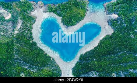 Luftaufnahme von oben auf Love Lagoon Karwapop mit türkisfarbenem Wasser in Herzform innerhalb der felsigen tropischen Insel auf Raja Ampat, Papua, Indonesien. Stockfoto