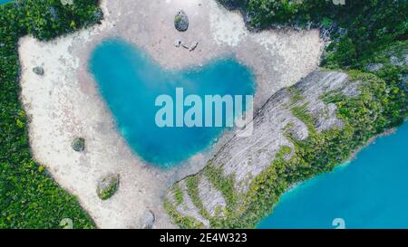 Luftaufnahme von oben auf Love Lagoon Karwapop mit türkisfarbenem Wasser in Herzform innerhalb der felsigen tropischen Insel auf Raja Ampat, Papua, Indonesien. Stockfoto