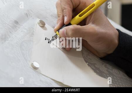 Ein Mann übt das Schreiben von Buchstaben in der Schrift einer Tora-Schriftrolle auf Pergament, (für den Herausgeber - hebräische Wörter haben keine Bedeutung und sind zufällige Buchstaben) Stockfoto