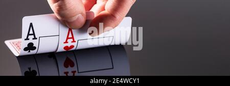 Eine Kombination aus zwei Assen spiegelt sich auf der Oberfläche eines schwarzen Hintergrundes und einer Männerhand wider. Stockfoto