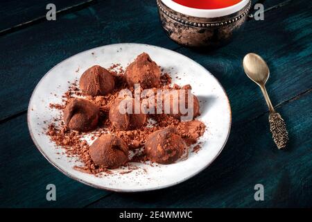 Schokoladentrüffel und Tee, elegantes Dessert auf einem dunklen Holztisch Stockfoto