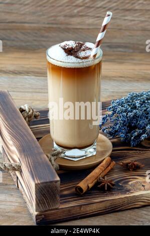 Kaffee Tasse Latte mit hausgemachtem Lavendelsirup und Blumen auf einem Holztablett. Gemütliches Frühstück Stockfoto