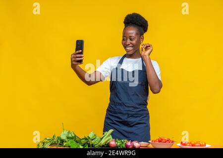 afrikanischer Koch macht Videoanruf, mit Zutaten vor ihr kochen Stockfoto