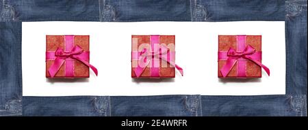 Rote Geschenkboxen in rechteckigem Rahmen aus dunkelblauen Jeans auf weißem Hintergrund eingeschlossen. Isoliert. Bannergröße. Speicherplatz kopieren. Einkaufen, Verkauf, Handel Stockfoto