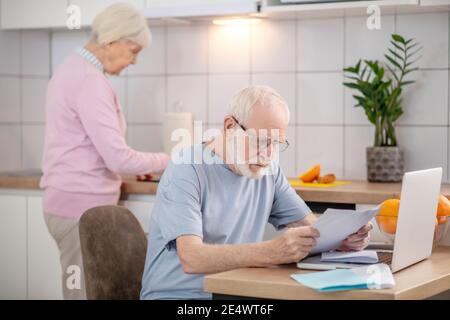 Bärtiger älterer Mann, der etwas liest und ernst aussieht Stockfoto