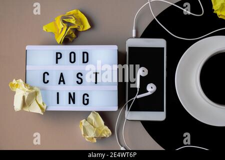 Podcasting-Schriftzug. Tasse schwarzen Kaffee auf vynil Rekord. Speicherplatz kopieren. Musik hören. Retro-Style. Podcast. Mobiltelefon mit Kopfhörern. Stockfoto