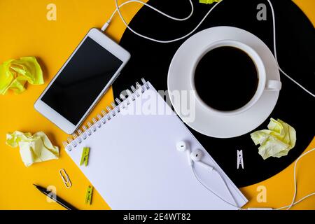 Tasse schwarzen Kaffee auf vynil Rekord. Speicherplatz für Notizbuch-Kopien. Musik hören. Retro-Style. Podcast. Mobiltelefon mit Kopfhörern. Stockfoto