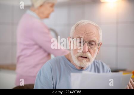 Bärtiger älterer Mann, der etwas liest und ernst aussieht Stockfoto