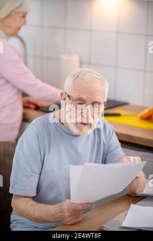 Bärtiger älterer Mann, der etwas liest und konzentriert aussieht Stockfoto
