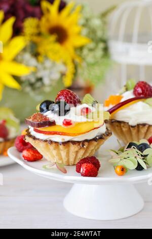 Schöne Cupcakes mit frischen Früchten verziert: Trauben, Pfirsich, Orange. Party-Dessert Stockfoto
