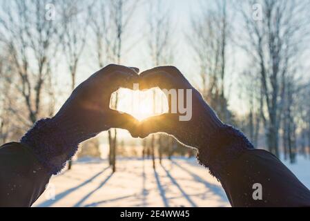 Valentinstag, Herz aus den Händen, Frau, die Herz Symbol.Valentinstag Tag.Sonnenuntergang Winter im Freien Hintergrund. Stockfoto