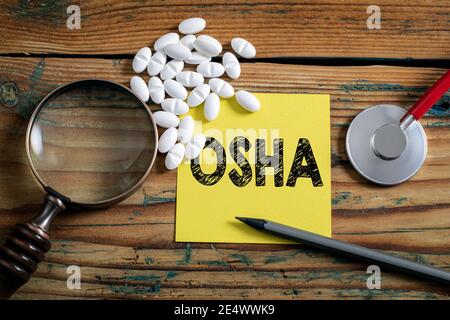 OSHA, Occupational Safety and Health Administration. Lupe auf einem Holzhintergrund. Stockfoto