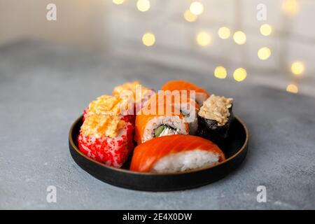Verschiedene Arten Set serviert Lachs Sushi-Rolle, Set serviert. Traditionelles asiatisches japanisches Essen auf schwarzem Teller auf Beton. Close up Selective soft Focus. Stockfoto