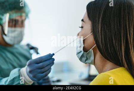 Medizinisches Personal, das persönliche Schutzausrüstung trägt und Corona-Viren-Tupfer macht Auf weibliche Patientin - Covid19 Test und Gesundheitskonzept Stockfoto