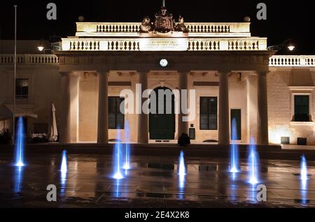 Farbige Jets Wasser von Brunnen und der Hauptwache Gebäude bei Nacht in Valletta, Malta Stockfoto